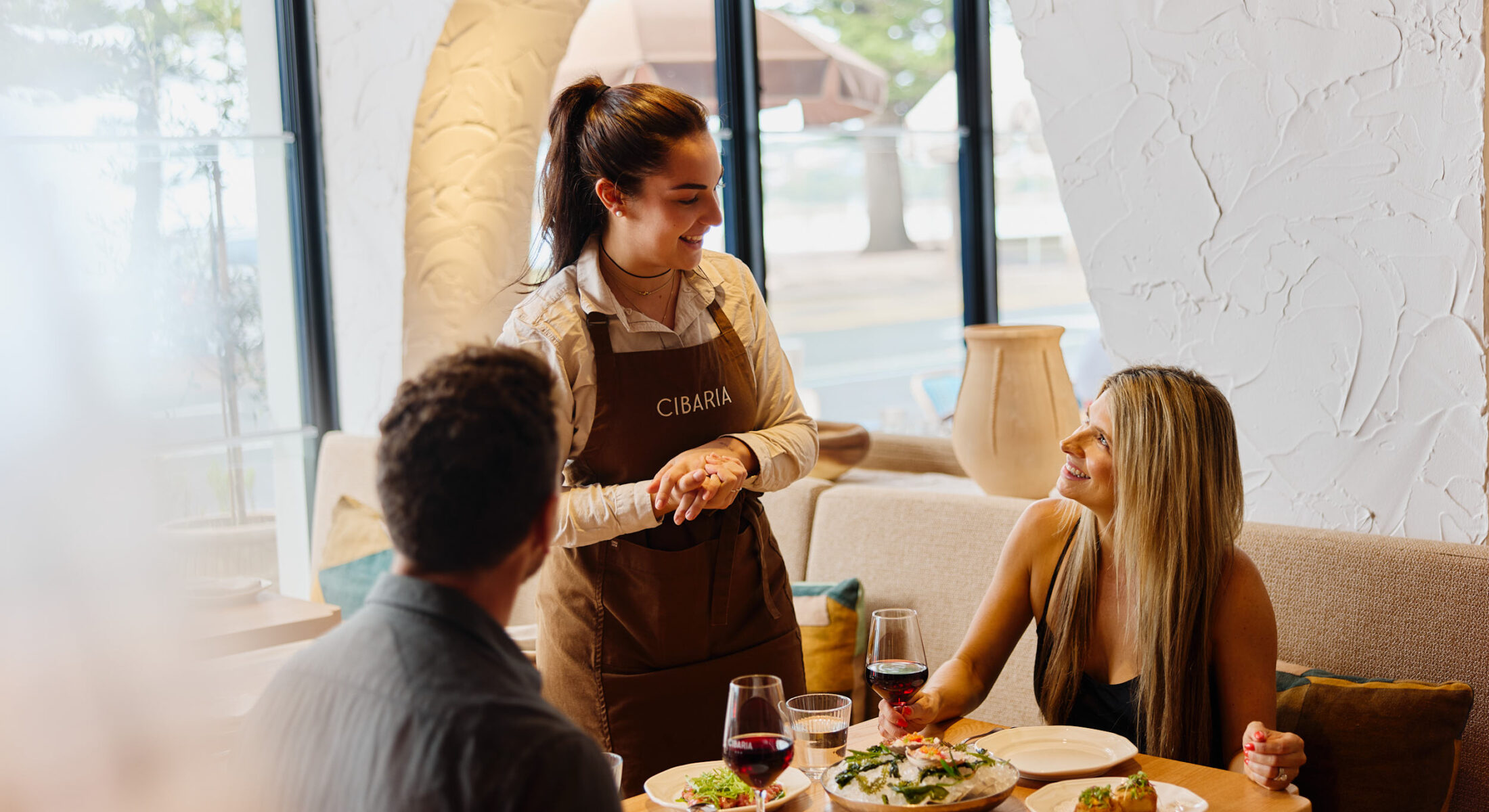 A waitress speaking to a couple dining at Cibaria