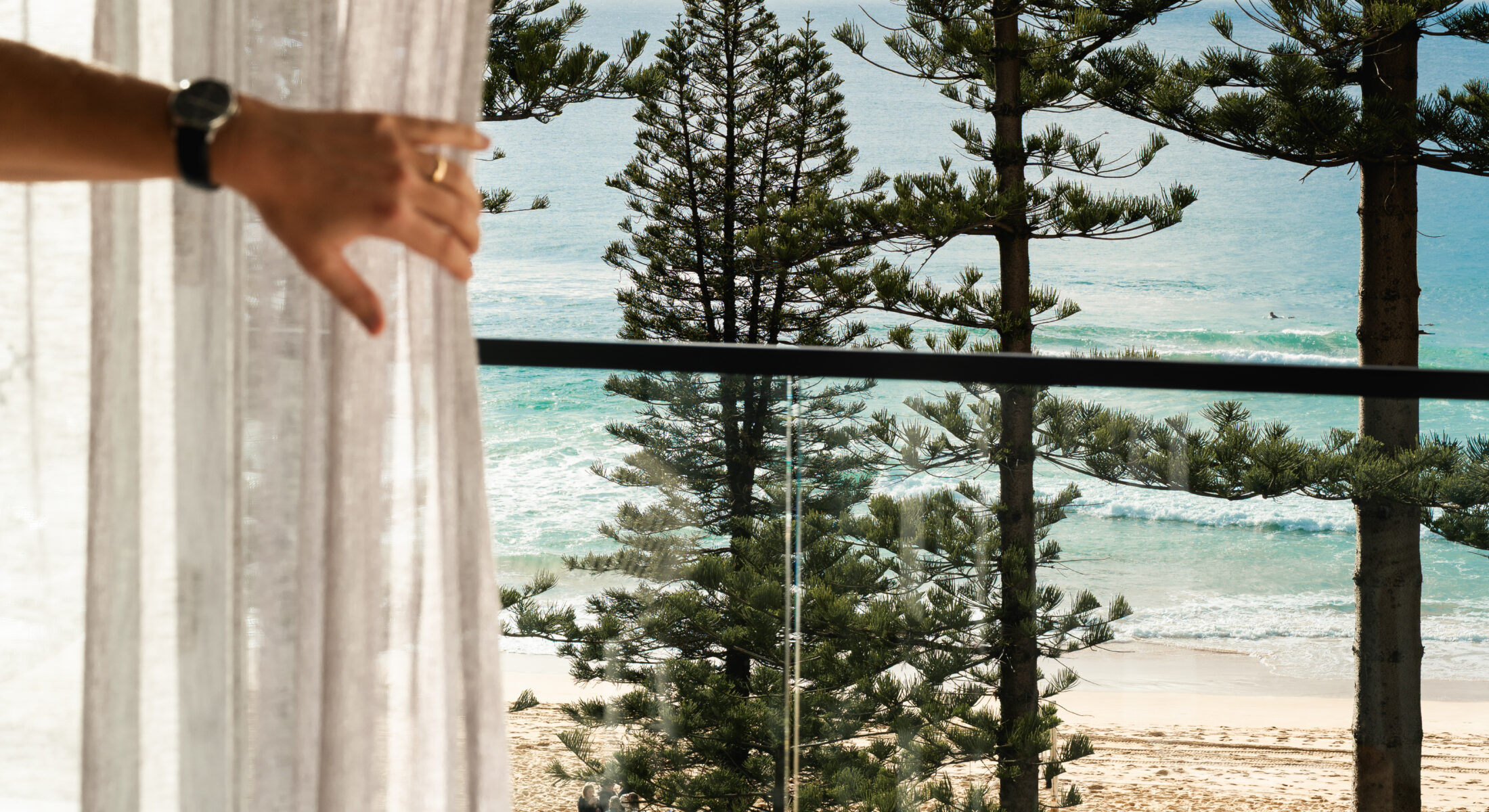 A man opening the curtain to his balcony